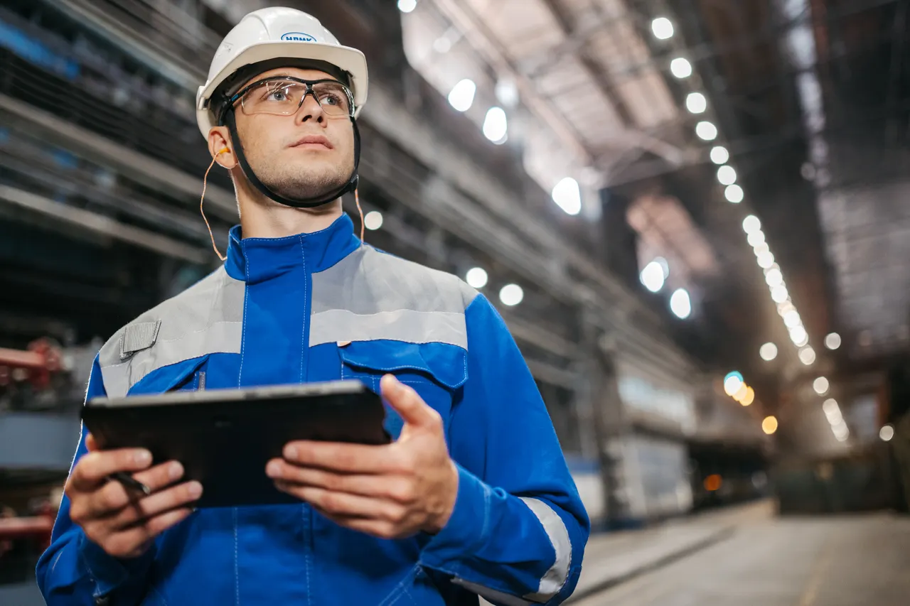 Professionnel en équipement de protection utilisant une tablette dans une usine